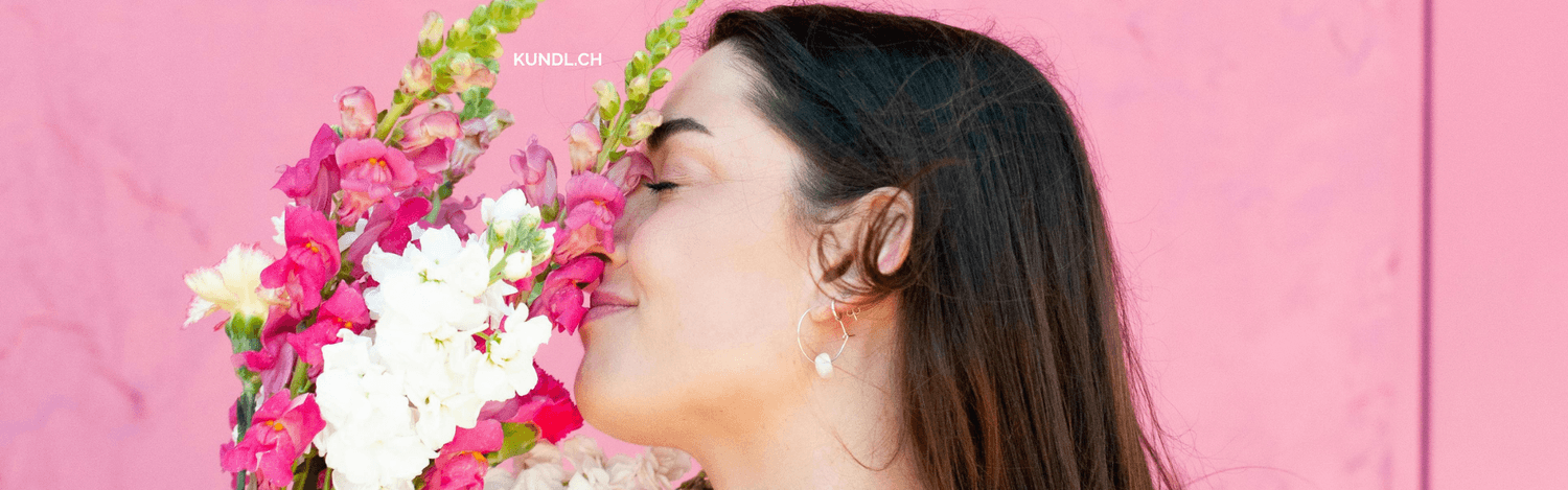 lächelnde Frau die an einem Blumenstrauss riecht