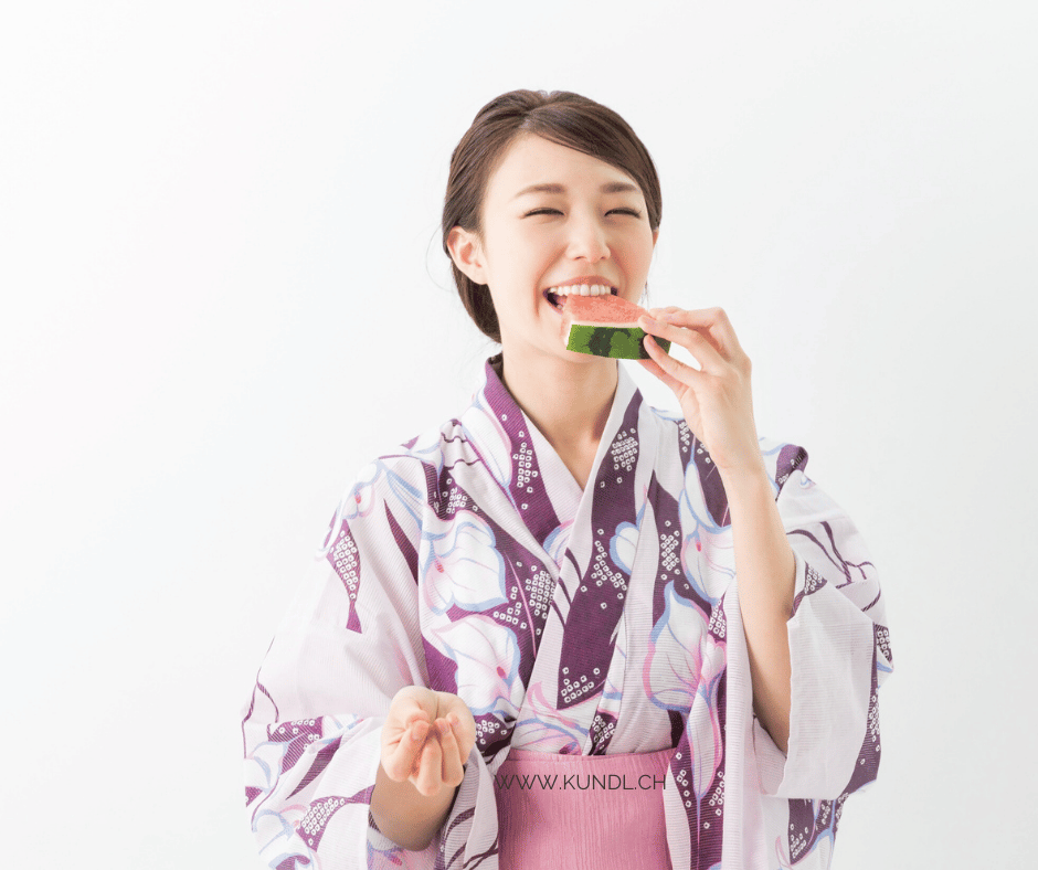 Frau die freudvoll in ein Stück Melone beisst