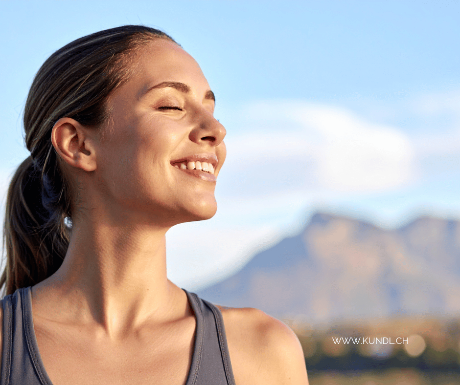 lächelnde Frau in aufrechter Haltung mit Sonne im Gesicht