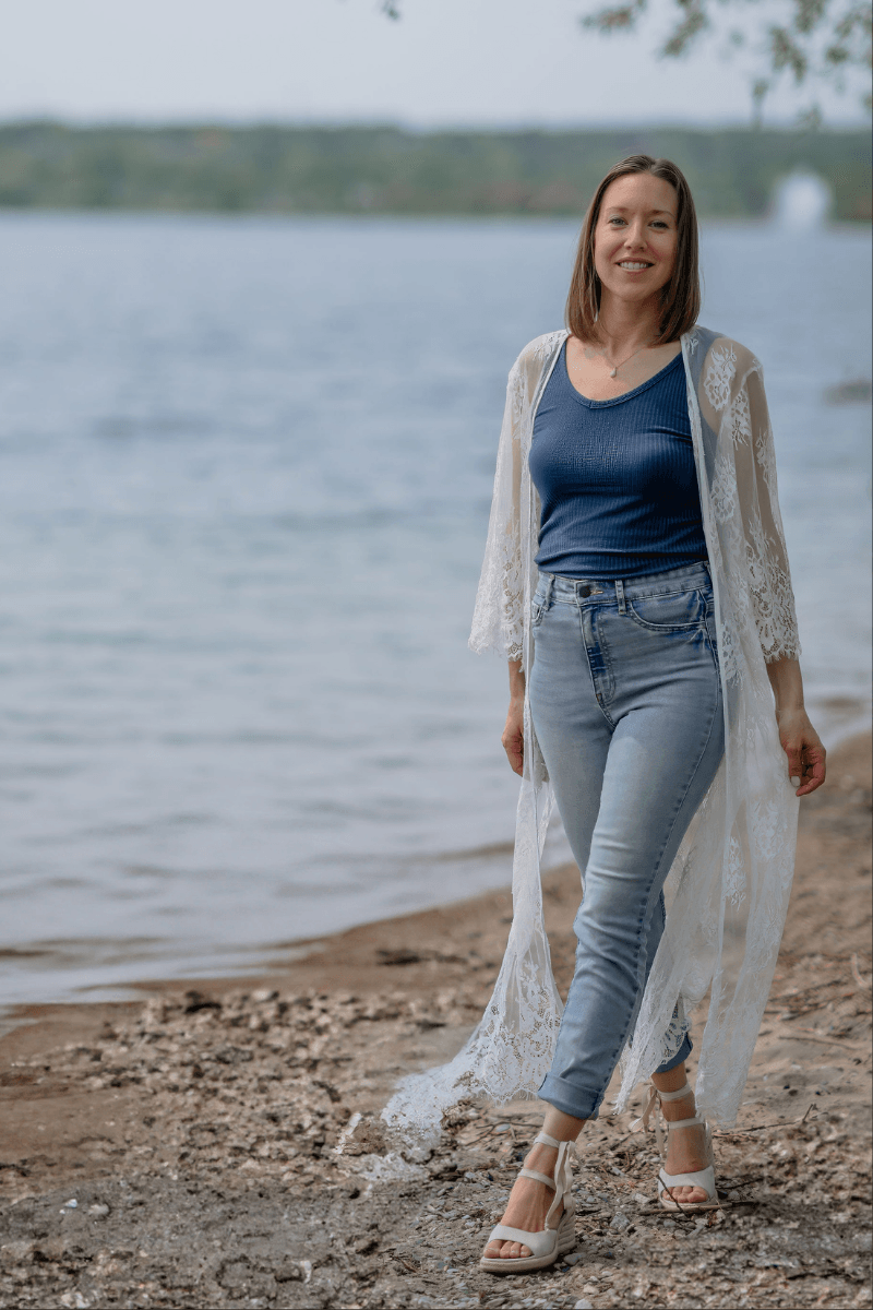 coach walking alongside water on rocky beach smiling at camera
