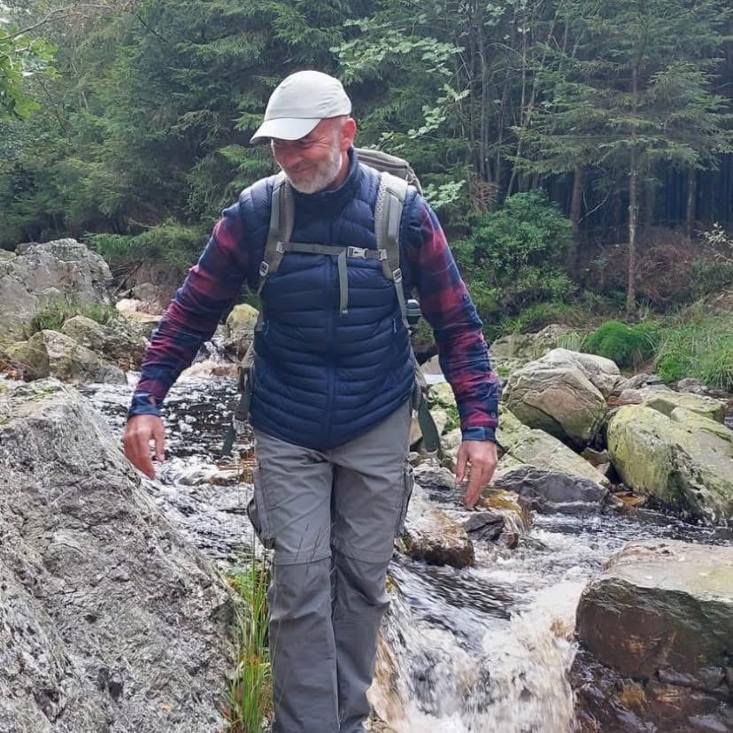 Philippe marche dans un ruisseau au cœur de la forêt