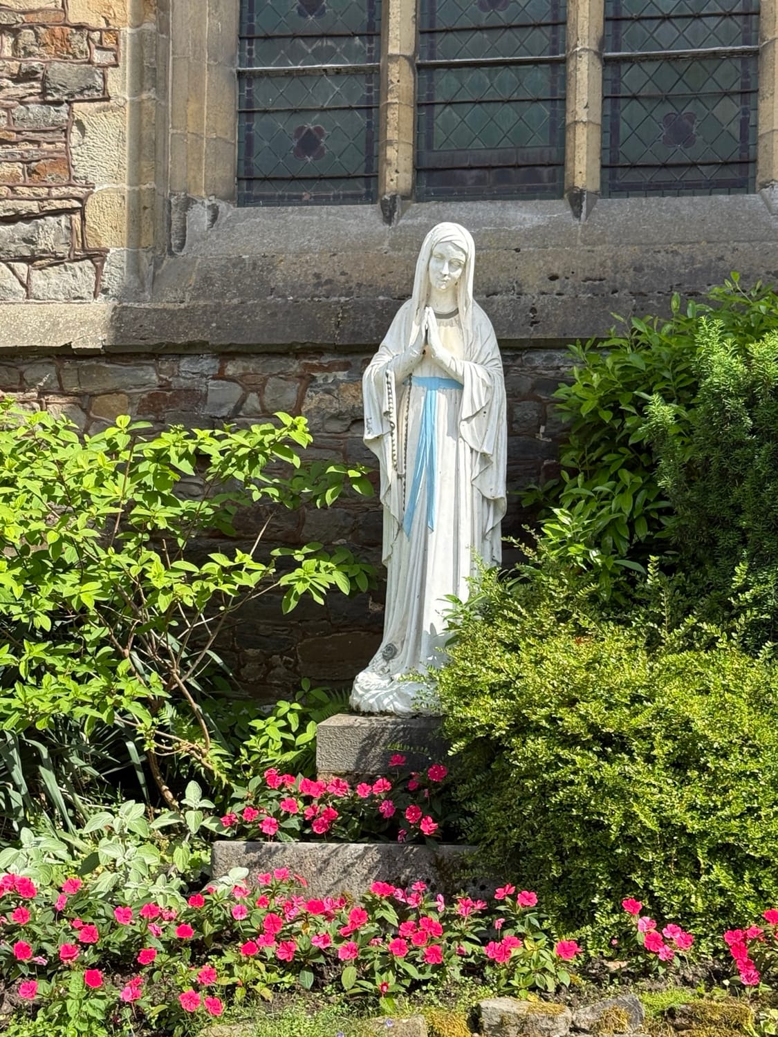 Statue de la Vierge Marie entourée de fleurs au Val-Dieu