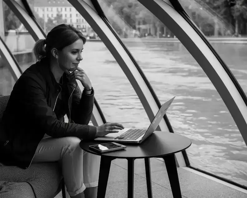 Femme concentrée devant son ordinateur portable à Graz, réfléchissant aux étapes d'une migration WordPress manuelle et complexe.