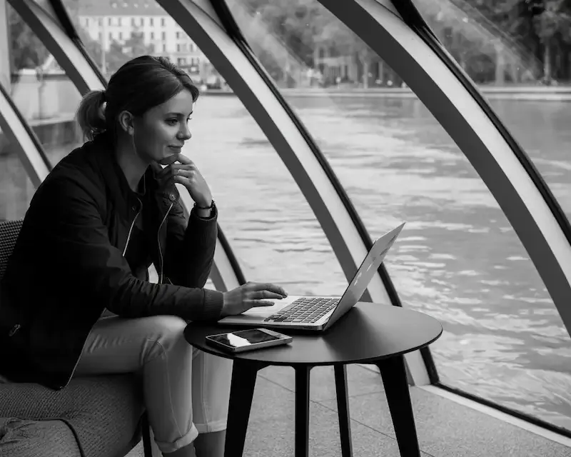 Femme concentrée devant son ordinateur portable à Graz, réfléchissant aux étapes d'une migration WordPress manuelle et complexe.