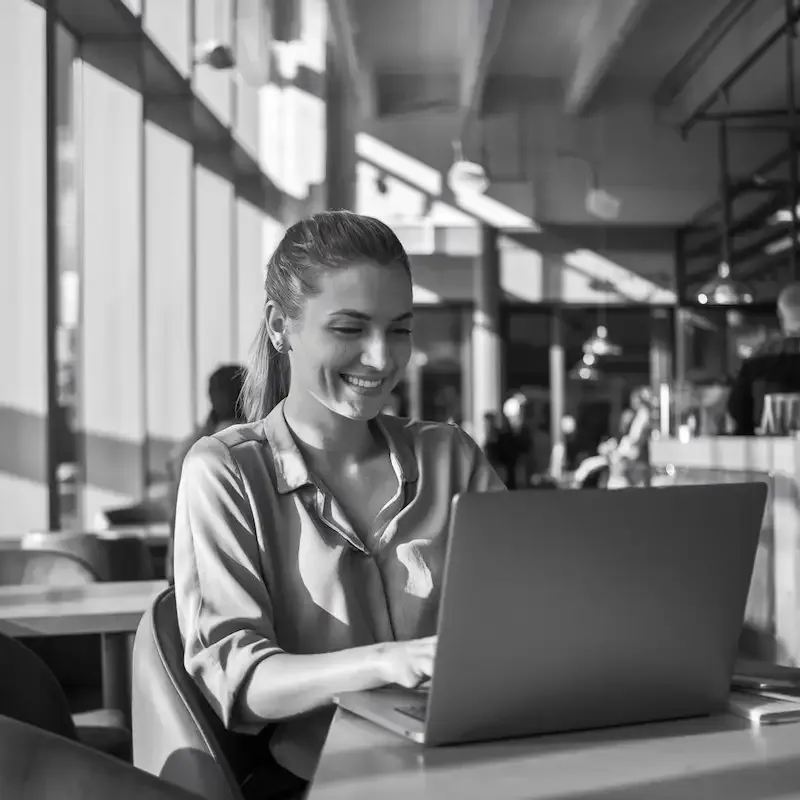 Entrepreneuse souriante analysant ses KPI SEO sur ordinateur portable dans un espace de coworking