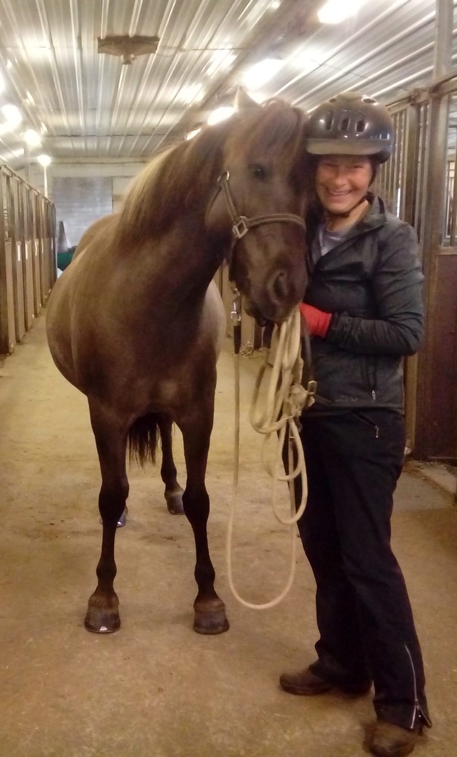 A soft-eyed blue dun mare nestled against her human in the stable, a moment of connection and serenity.