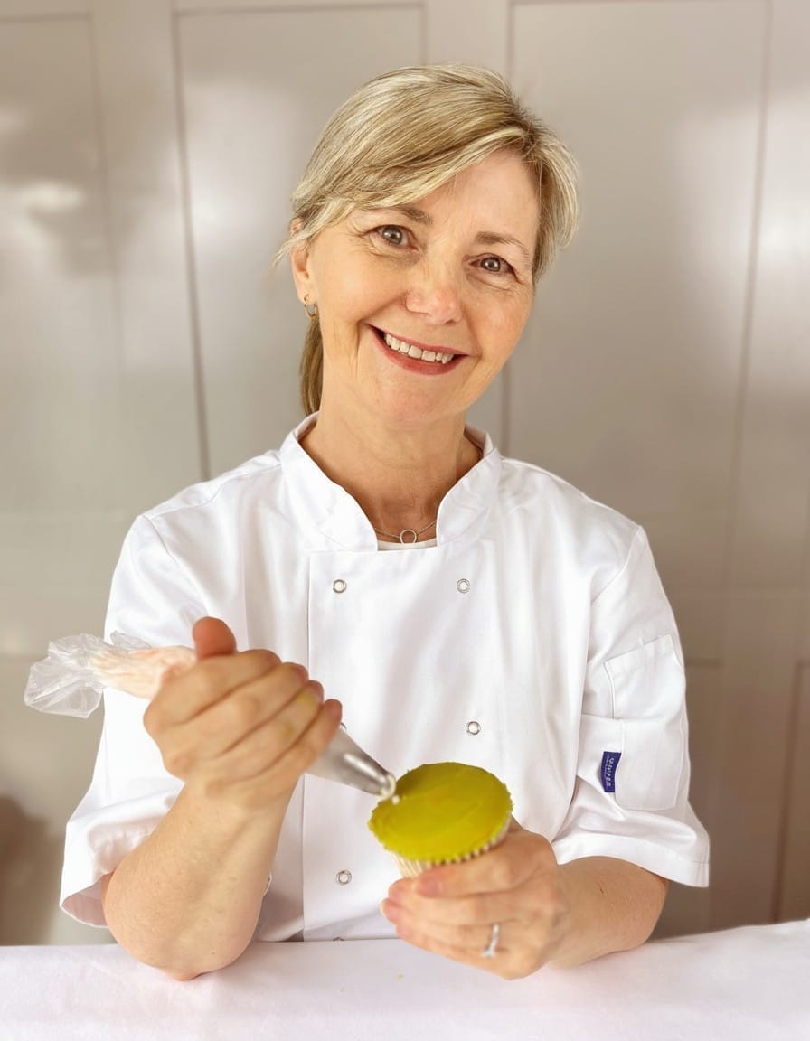 Sharon Burchall Cake Studio Hand piping a buttercream swirl onto a cupcake during a decorating demo