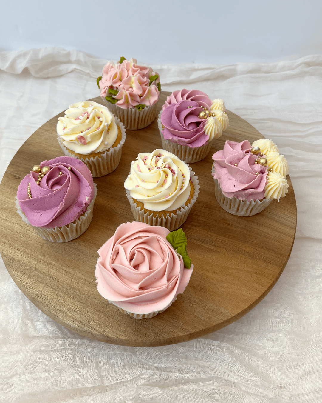 upcakes decorated with buttercream swirls and simple flowers, arranged in a small display.