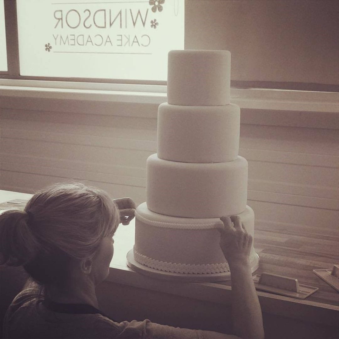 Sharon Burchall, founder of Sharon Burchall Cake Studio — decorating a cake while working at Windsor Cake Craft, teaching classes, supporting customers, and sharing cake decorating knowledge.