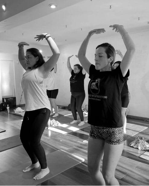 Alumnas en clase de hipopresivos con los brazos arriba
