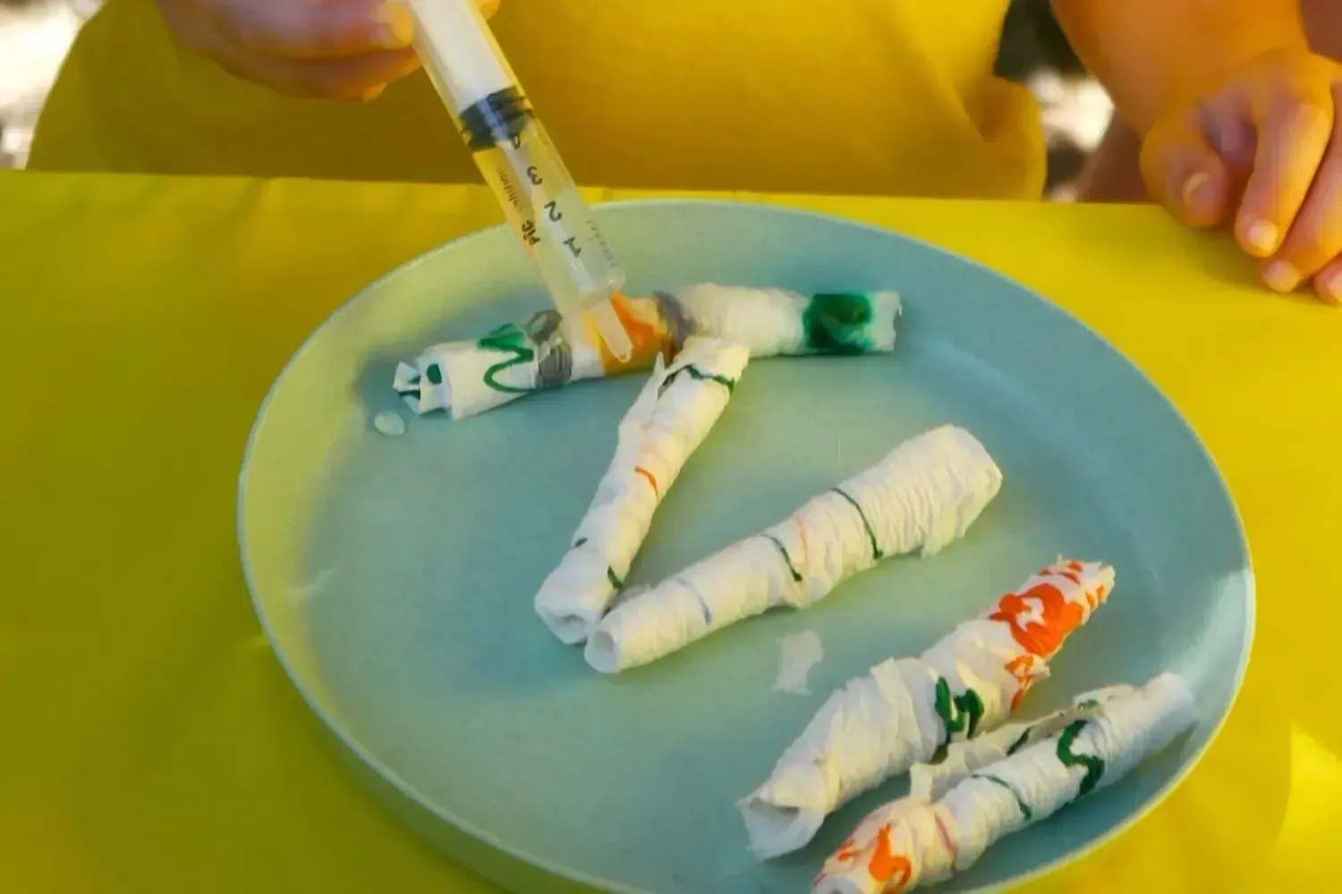 Experimento infantil con jeringa y papel enrollado durante la Feria de la Ciencia de Talentiaex, actividad práctica de ciencia para niños y niñas