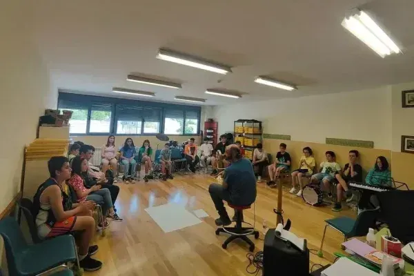 Taller de música con adolescentes durante el programa Talentiaex, guiado por un facilitador en un aula con disposición en círculo y ambiente participativo