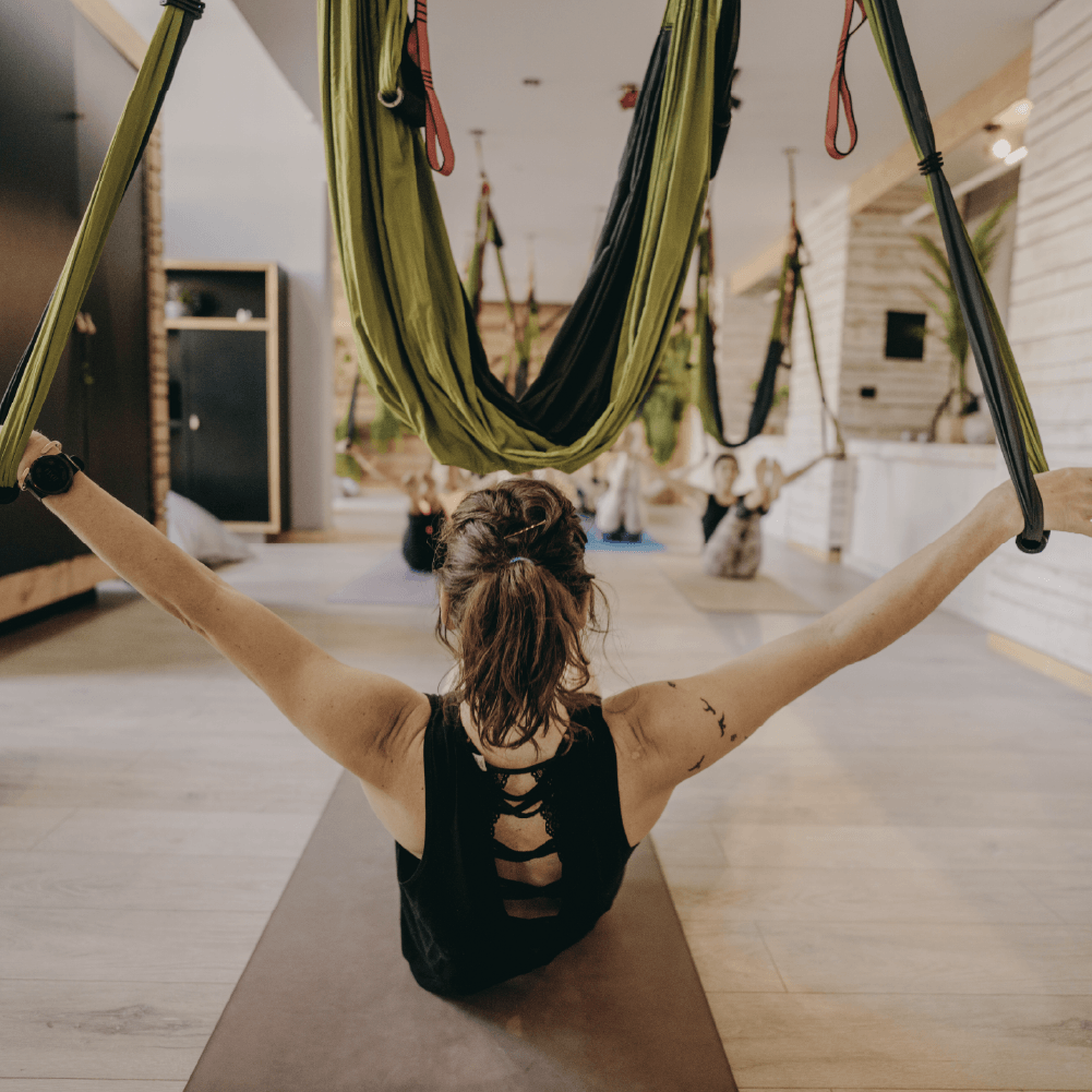 Maestra de AeroYoga® en formación, usando columpio aéreo en clase presencial