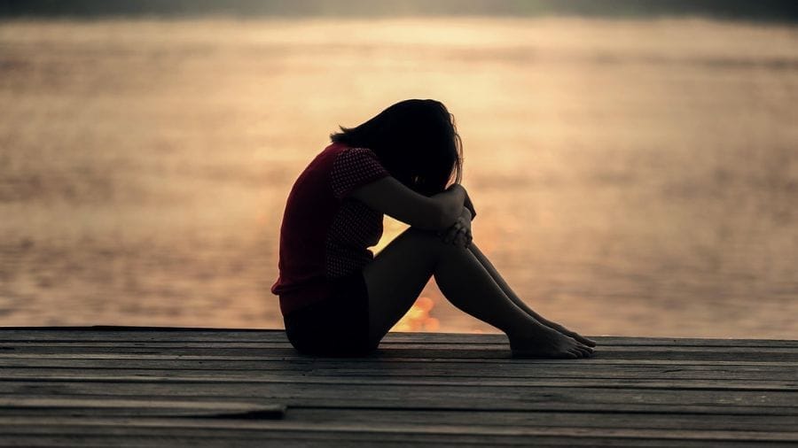 Vrouw zit ineengevouwen op de grond – beeld van stress, verlamming en overweldiging bij ADHD