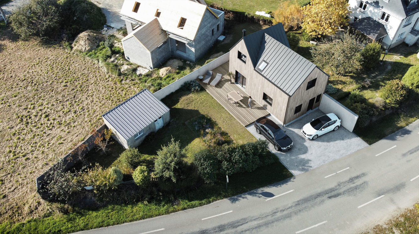 Insertion 3D paysagère en vue aérienne d'une maison moderne à bardage bois avec terrasse et jardin aménagé dans son environnement urbain.