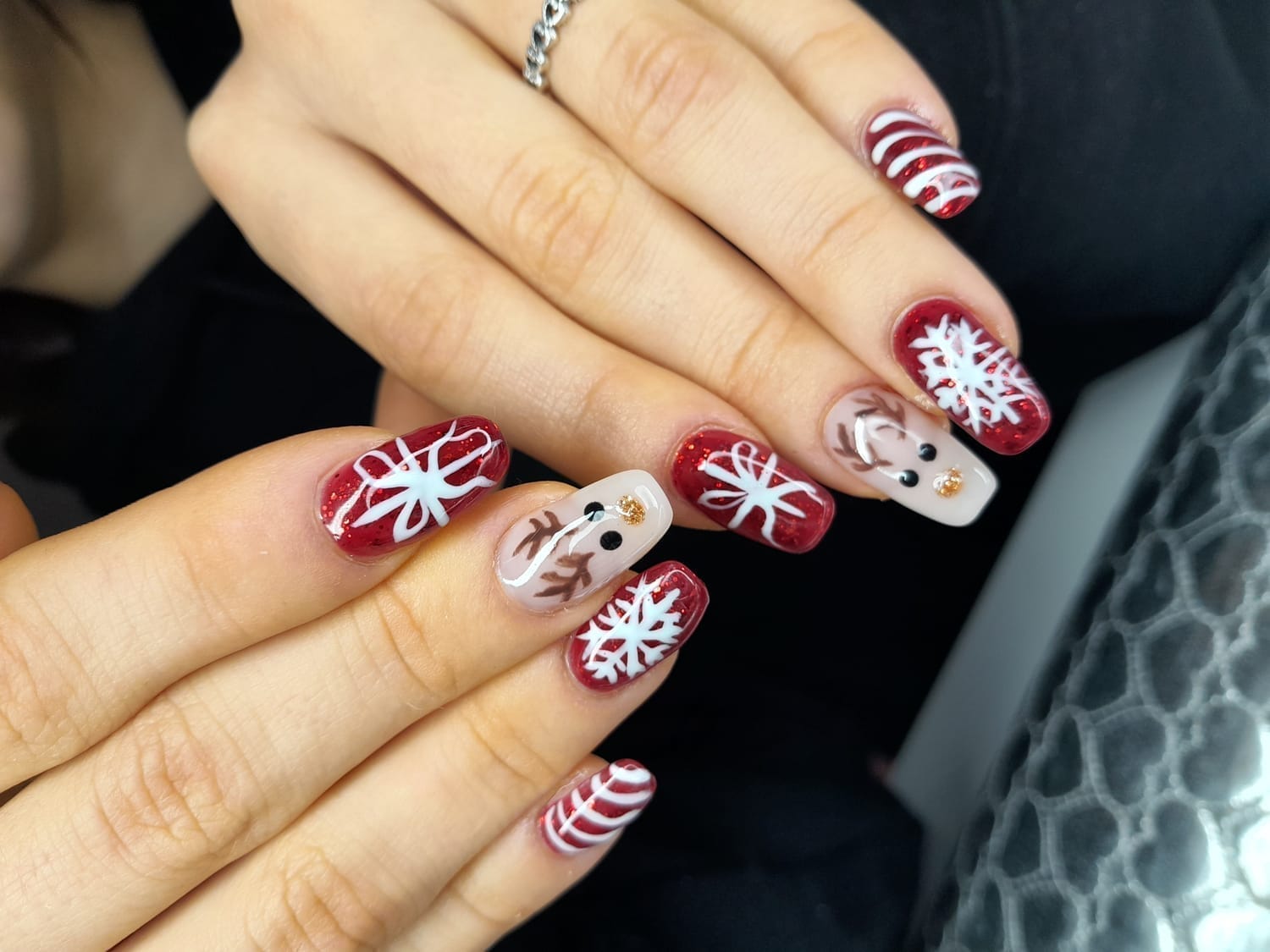 Nail art de Noël rouge et blanc sur ongles en gel, avec dessins de flocons, bonbons et rennes, manucure festive réalisée par une prothésiste ongulaire