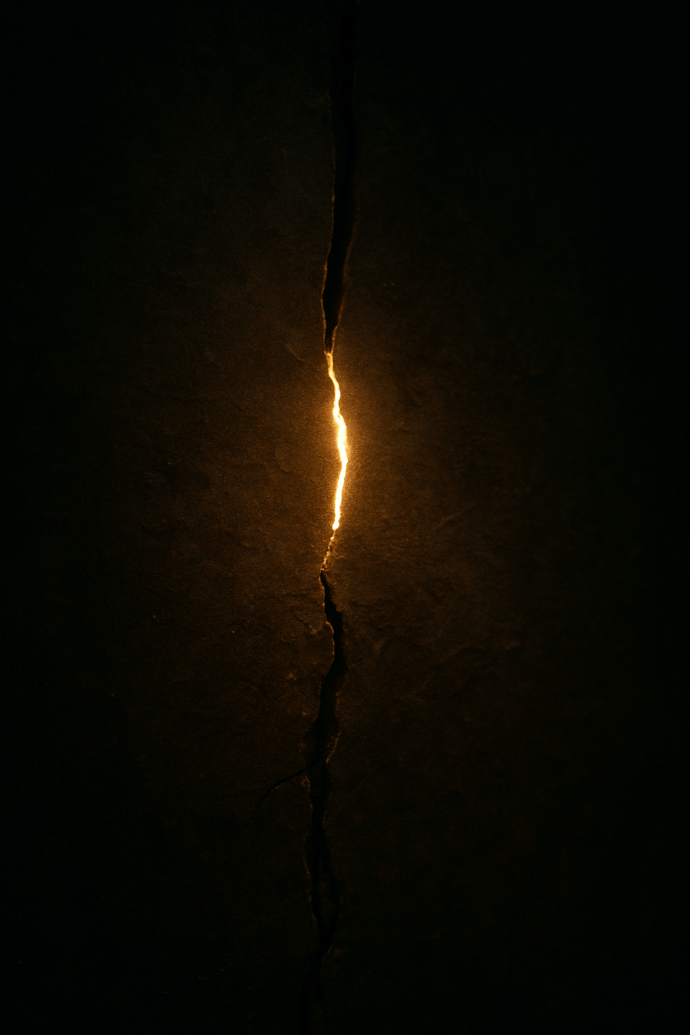 A narrow crack in a dark, textured wall softly illuminated by warm golden light breaking through — symbolizing hope, release, and the first gentle opening into healing.