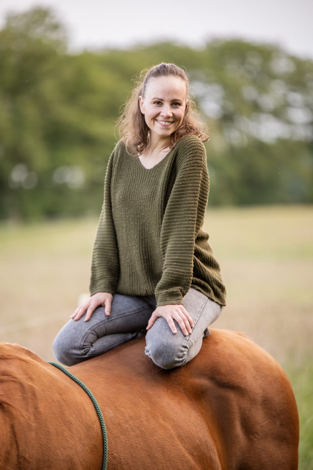 Tanja sitzt draußen auf einem Pferd