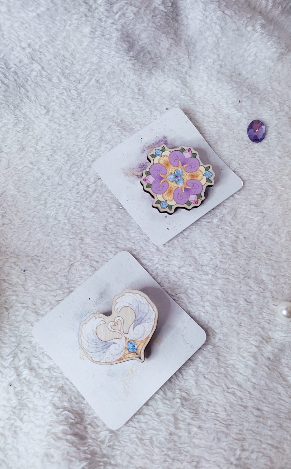 Deux pin's en bois, l'un en forme de fleur et l'autre en forme de cygne