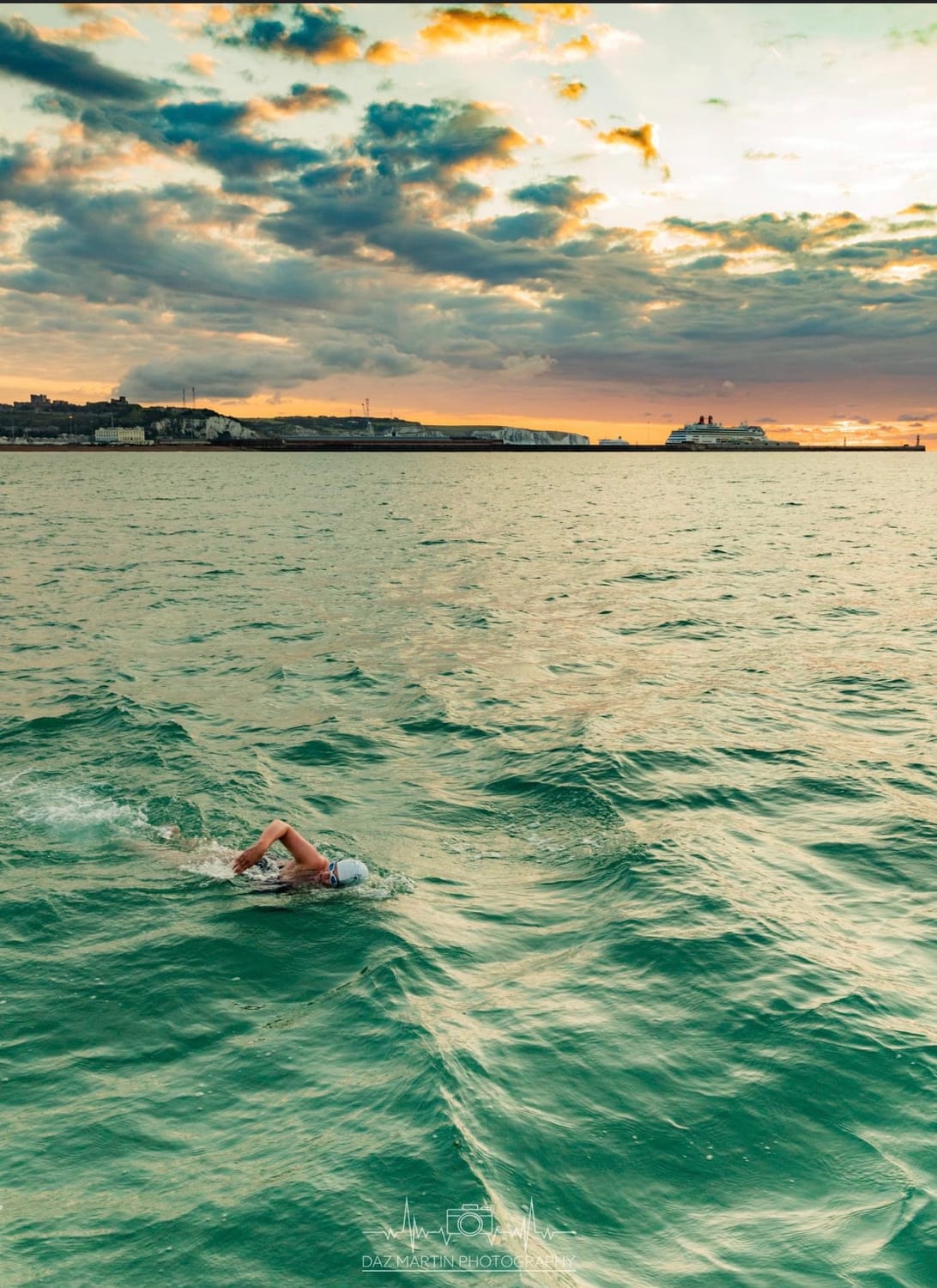 Smooth stones balanced on top of one another within blue water. The stones reflect in the water, with a slight ripple around the stones.