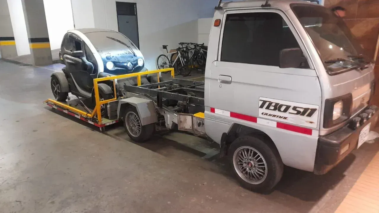 Motogrua llevando un carro electrico