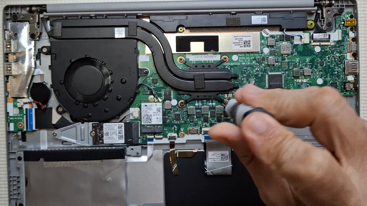 Laptop abierta en una clase práctica real de KAMBIG mostrando placa base, sistema de refrigeración y componentes internos