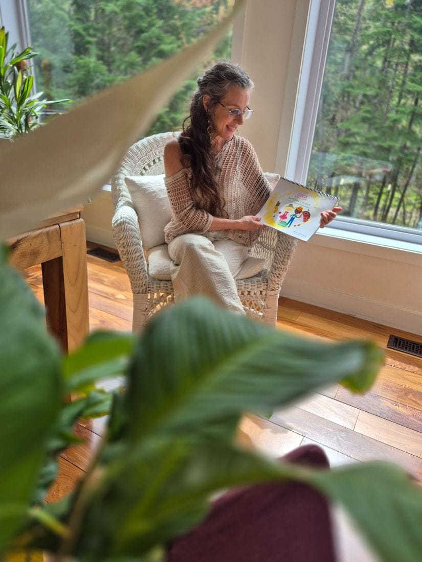 Annie Laberge lit le livre La ferme à Ti-Guy, assise près d’une grande fenêtre donnant sur la forêt.