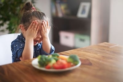 Enfant qui refuse de regarder son assiette de légumes