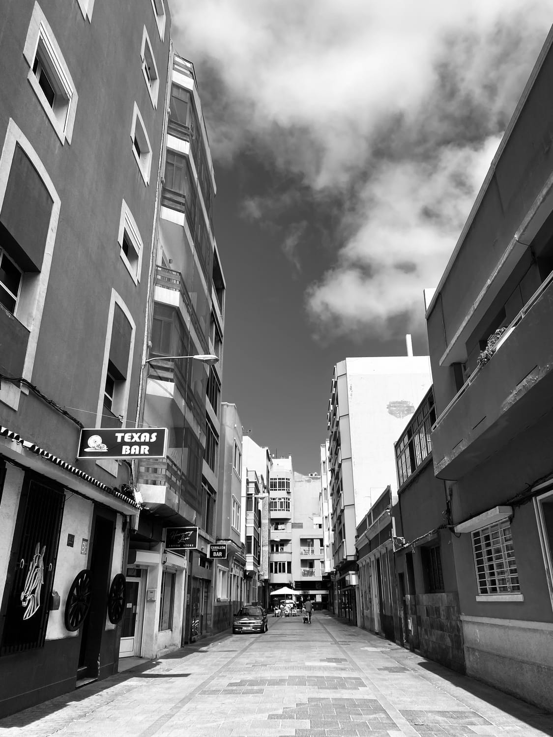 Black and white street view in Las Palmas, Gran Canaria, with local bars, narrow alleys, and sunlit architecture—capturing bespoke island itineraries, soulful cultural travel, and luxury experiences curated by a boutique travel planner.