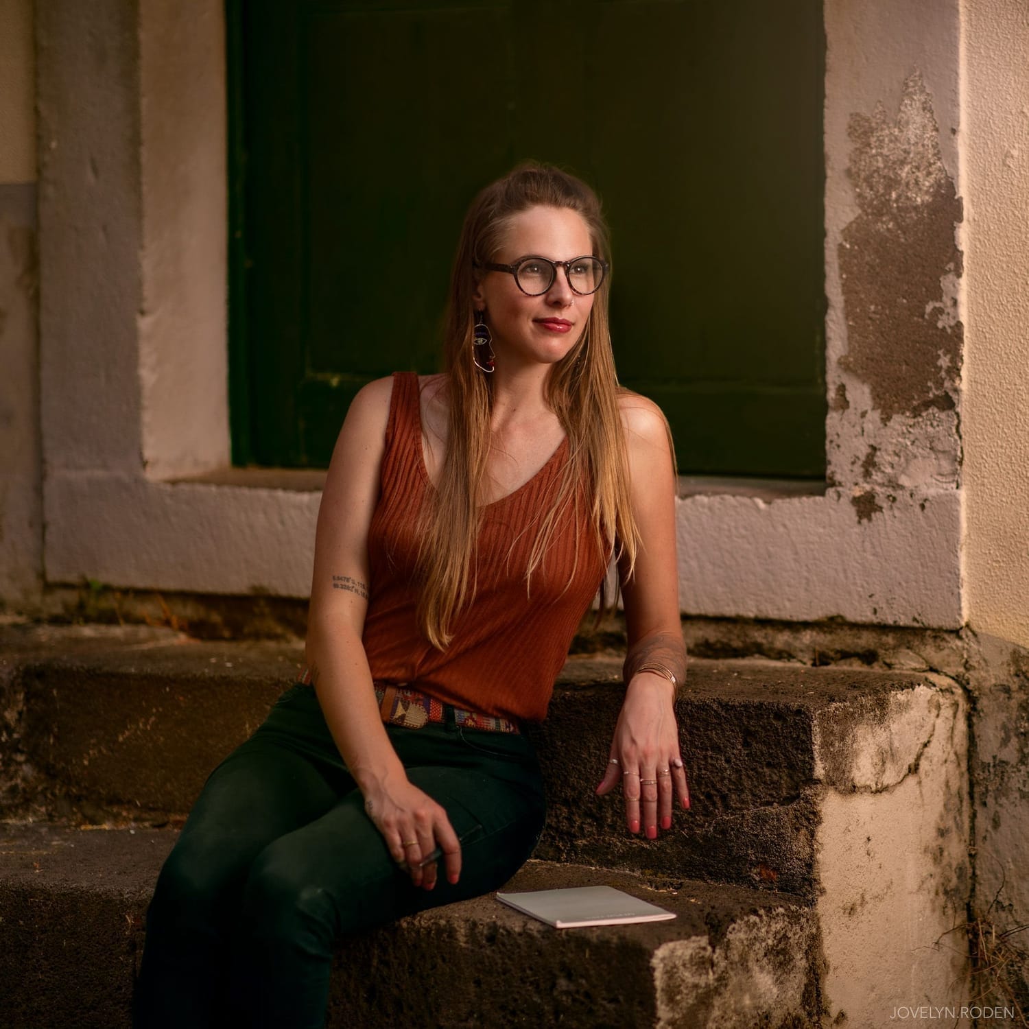 Danielle Blum, multi-genre author and creative entrepreneur, sitting outdoors on stone steps with a notebook nearby. She is known as a psychological thriller and rom-com author, boutique travel planner, retreat host, and book coach. Danielle also creates ADHD-friendly planners, shadow work journals, and digital productivity tools, helping writers, travelers, and creatives live boldly and intentionally.