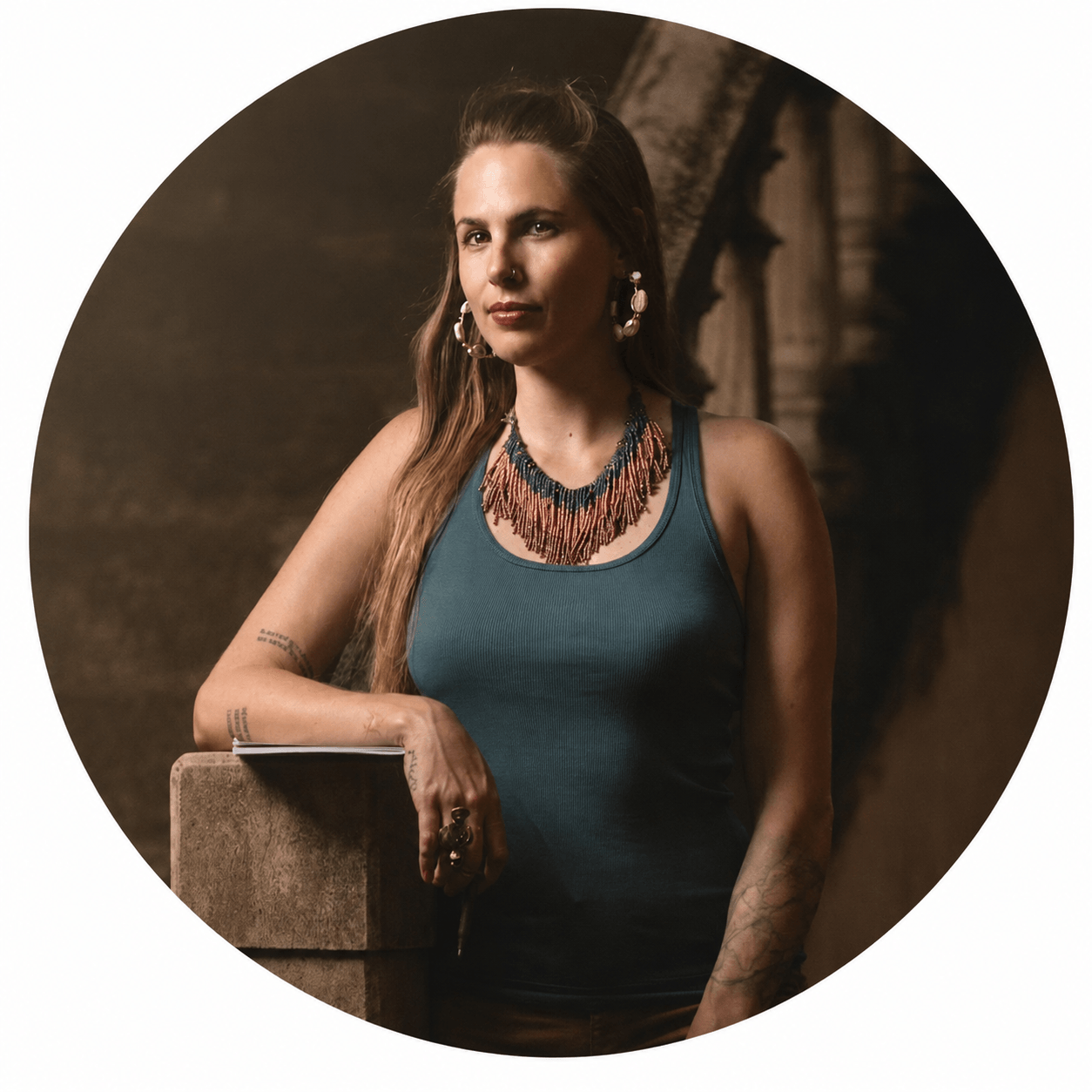 Author Danielle Blum in a teal top, leaning on a stone pillar.