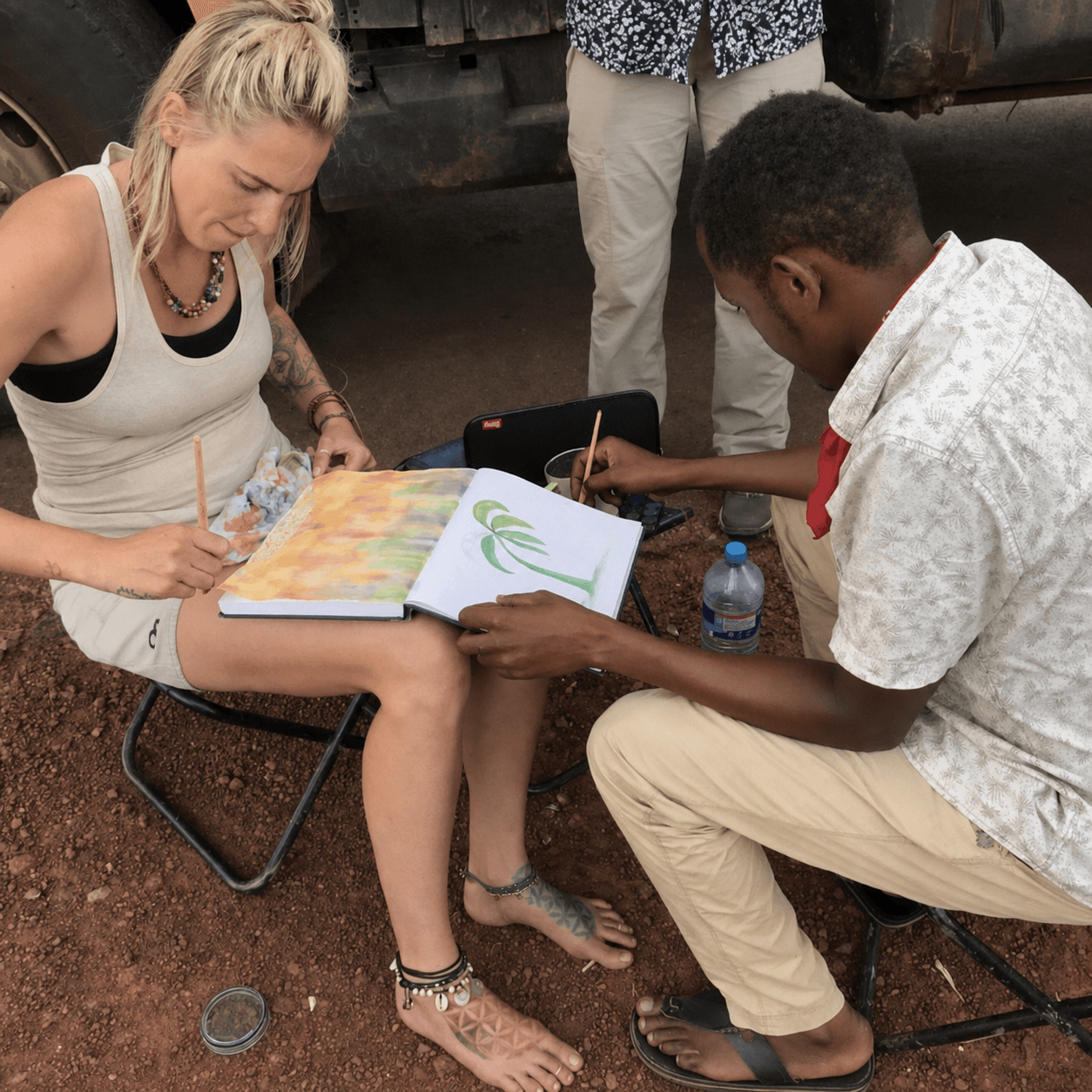 Danielle Blum and another artist painting together in an open sketchbook.