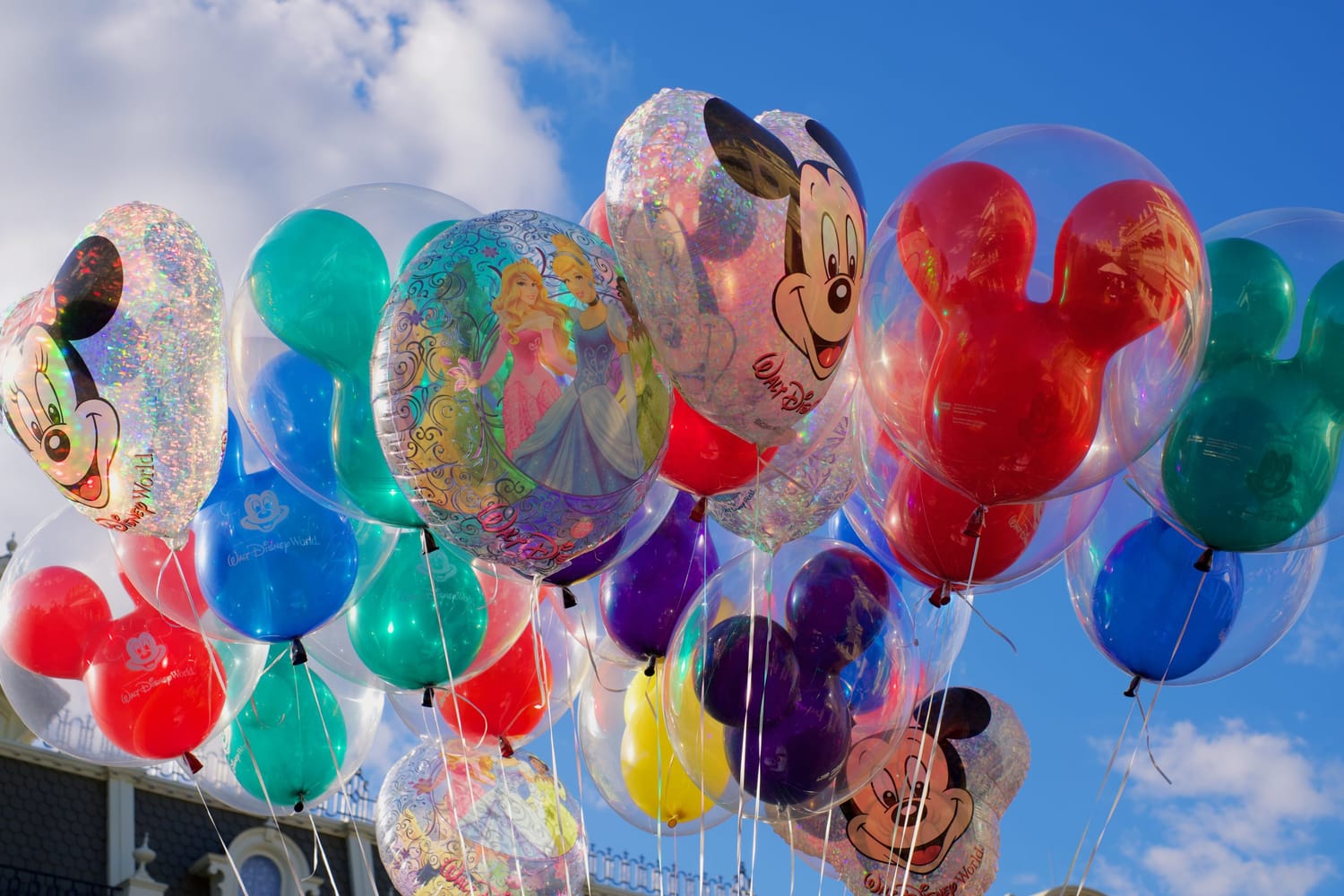 Colorful Disney character balloons against a bright blue sky