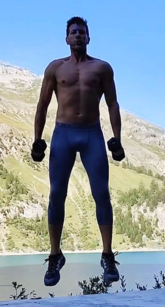 Alexis Reynaud en saut avec deux haltères dans les Alpes