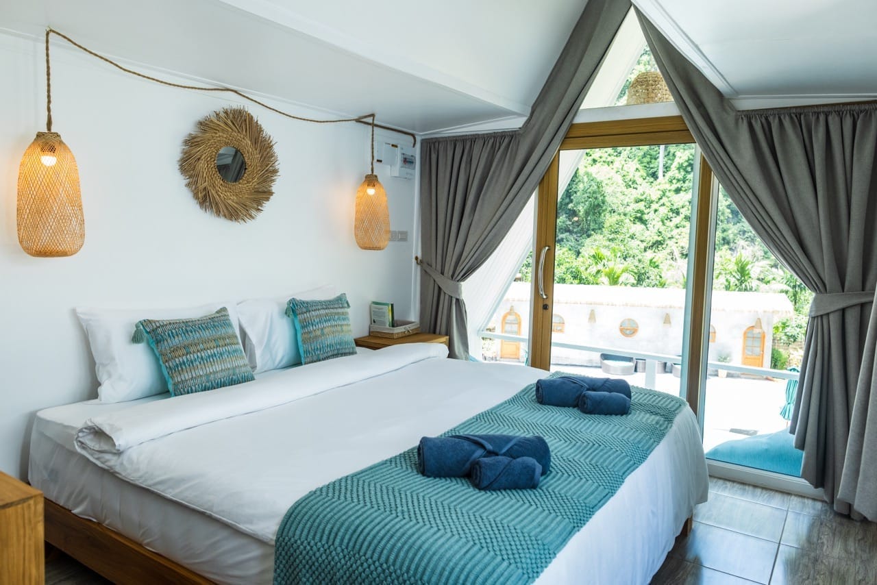 Helles Schlafzimmer im Bungalow mit großem Fenster und Naturblick