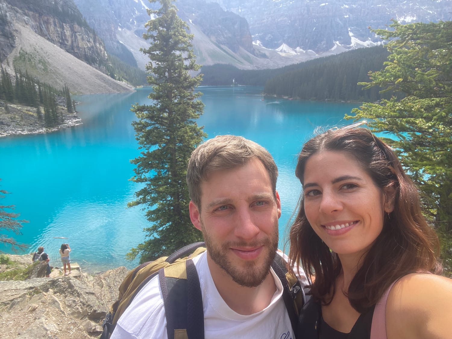 couple en voyage devant un lac turquoise dans les montagnes