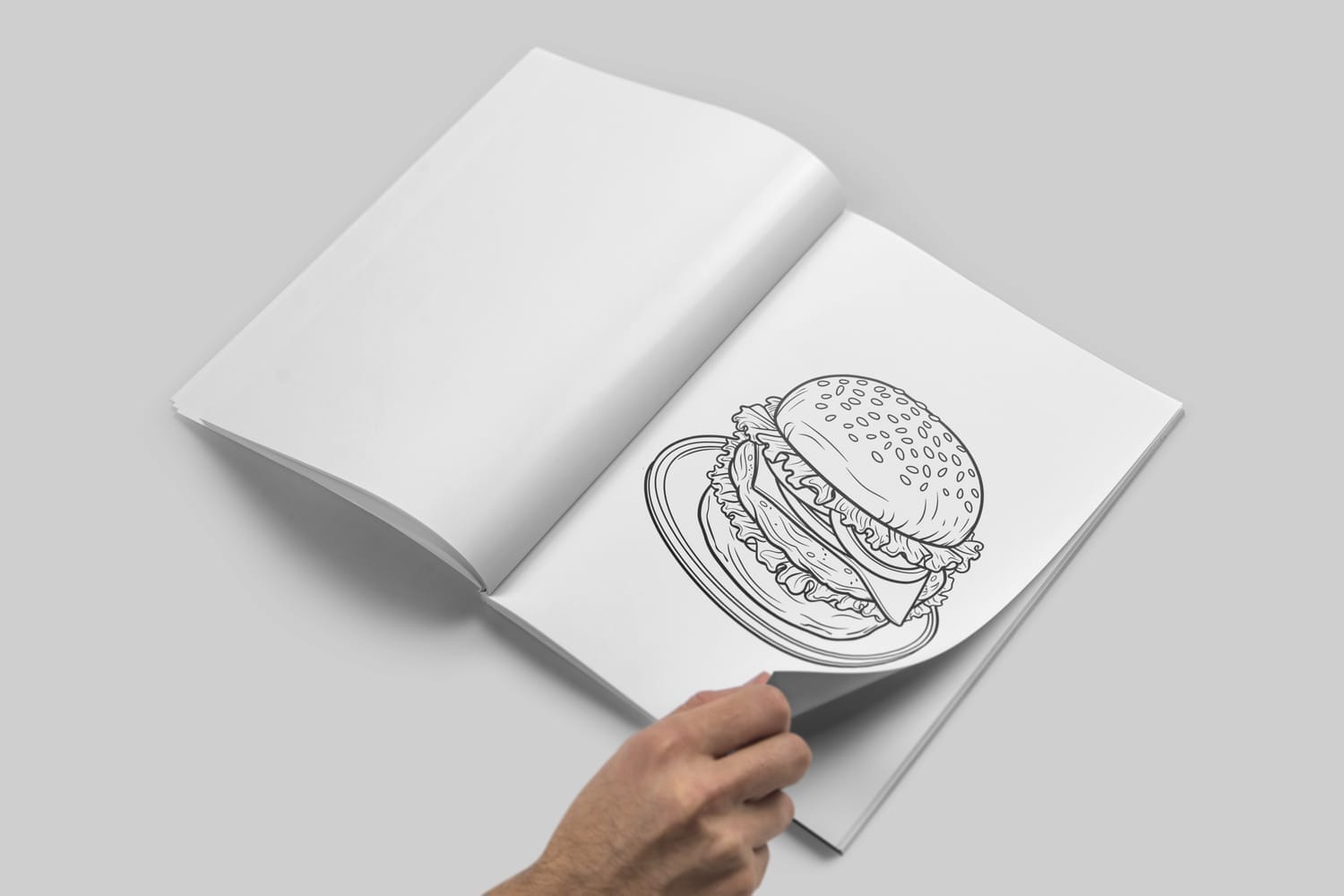 Open coloring book with a detailed hamburger line drawing on a plate, as a hand turns the page against a gray background.