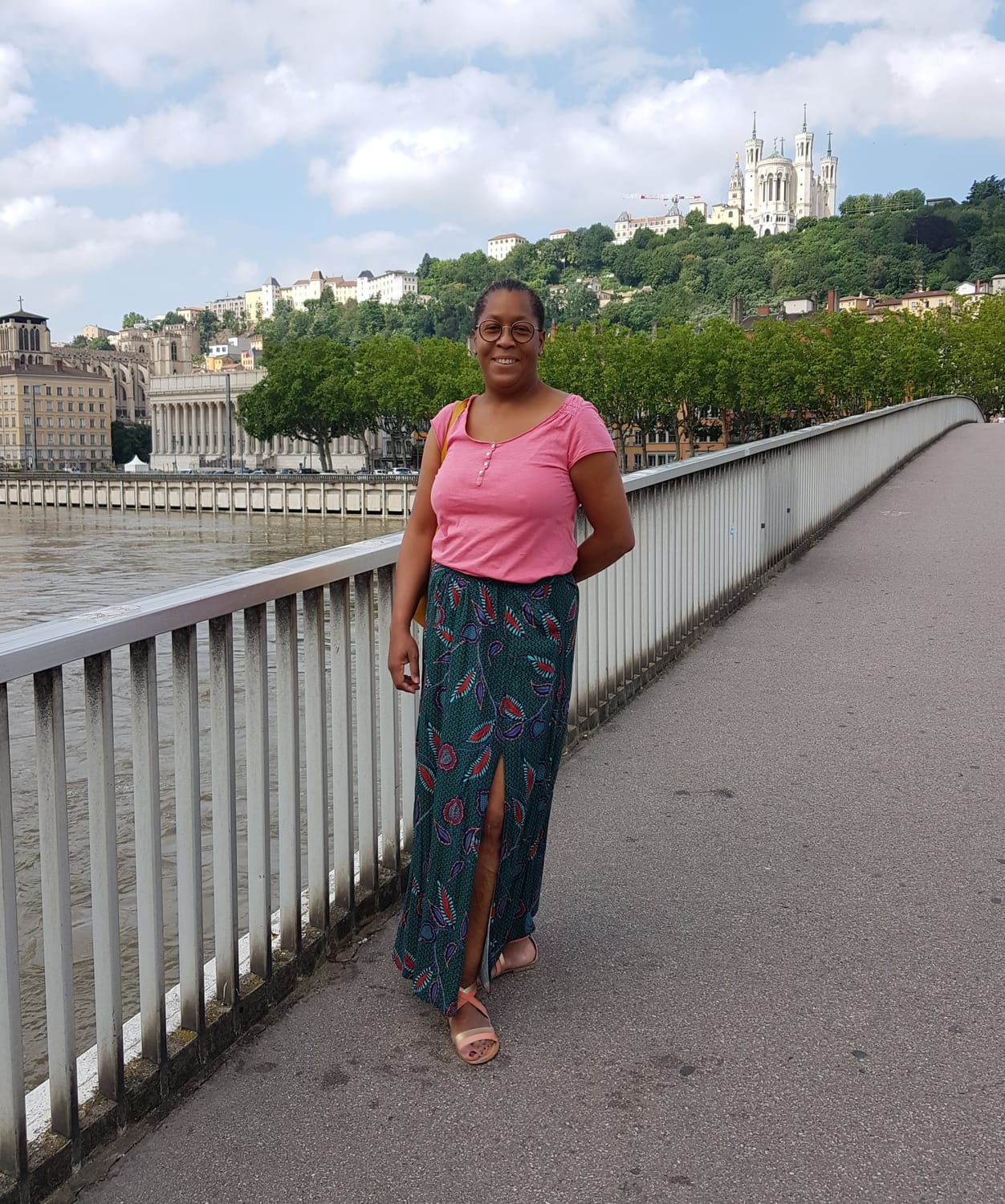 Krys, coach en Human Design, souriante sur une passerelle au bord de la Saône à Lyon