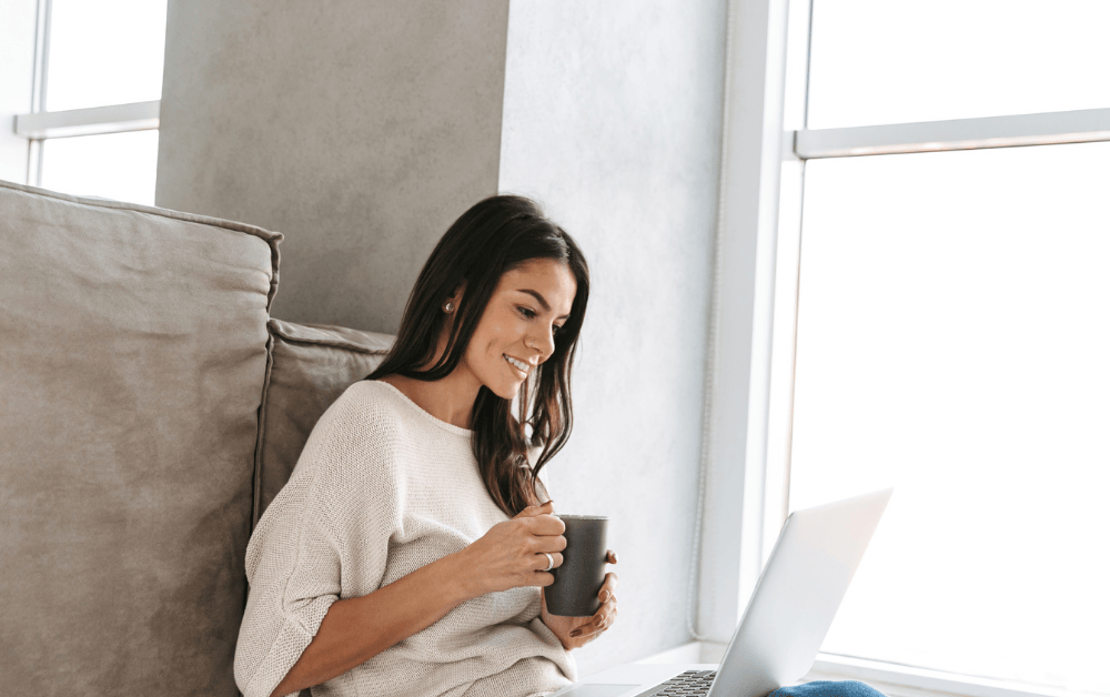 Frau mit Kaffee vor Laptop entdeckt smarte Spartipps mit KI – Familienbudget clever nutzen