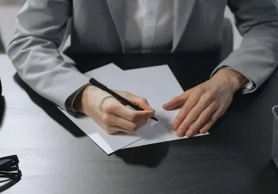 Manos de hombre escribiendo en una hoja en blanco