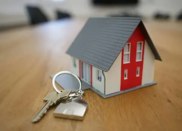 Llavero con la figura de una diminuta casita colocado sobre una mesa de madera