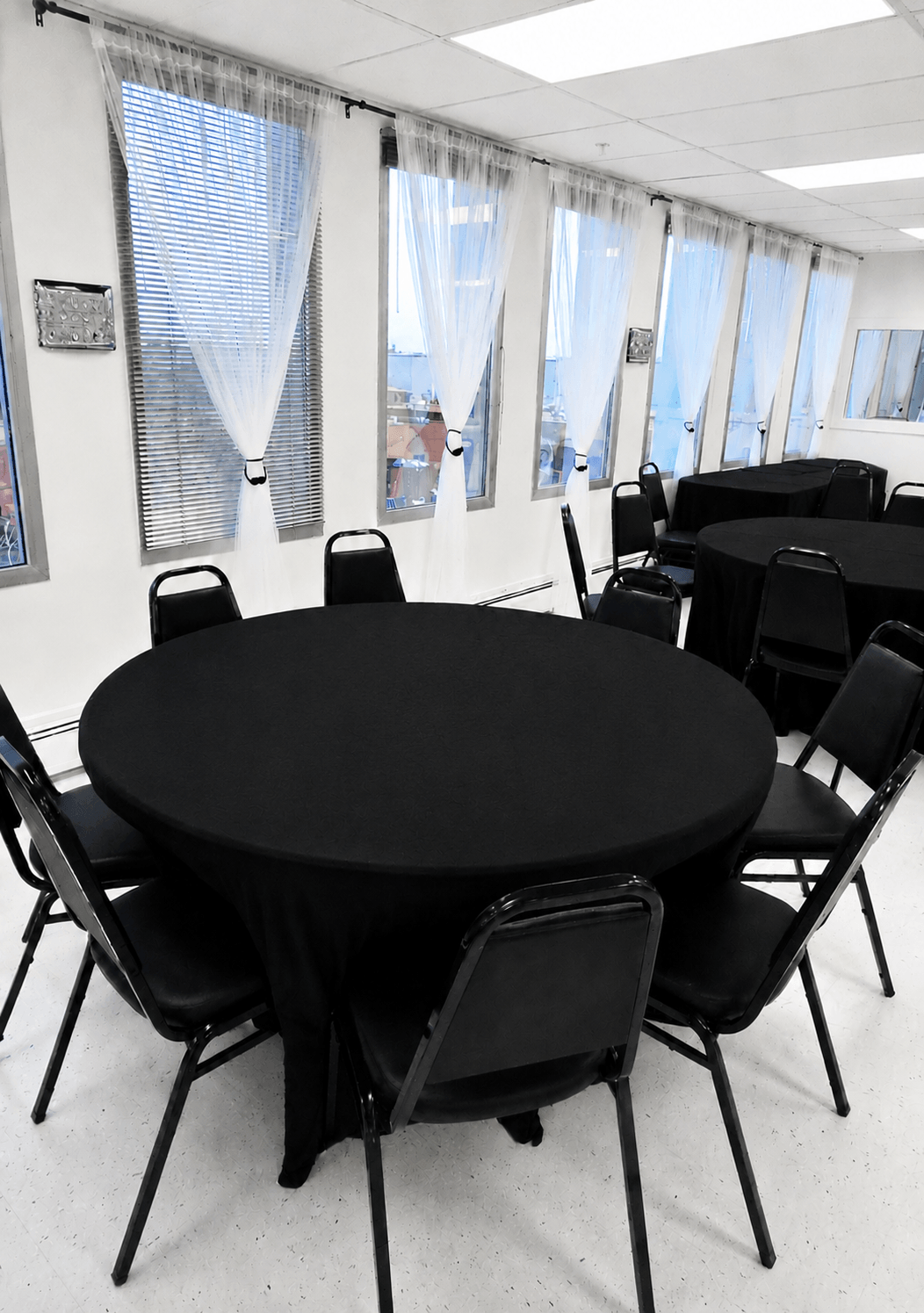 Repass Package & Celebration of Life Package with circular tables, black tablecloths and black banquet chairs set up at TD Event Space in Denver