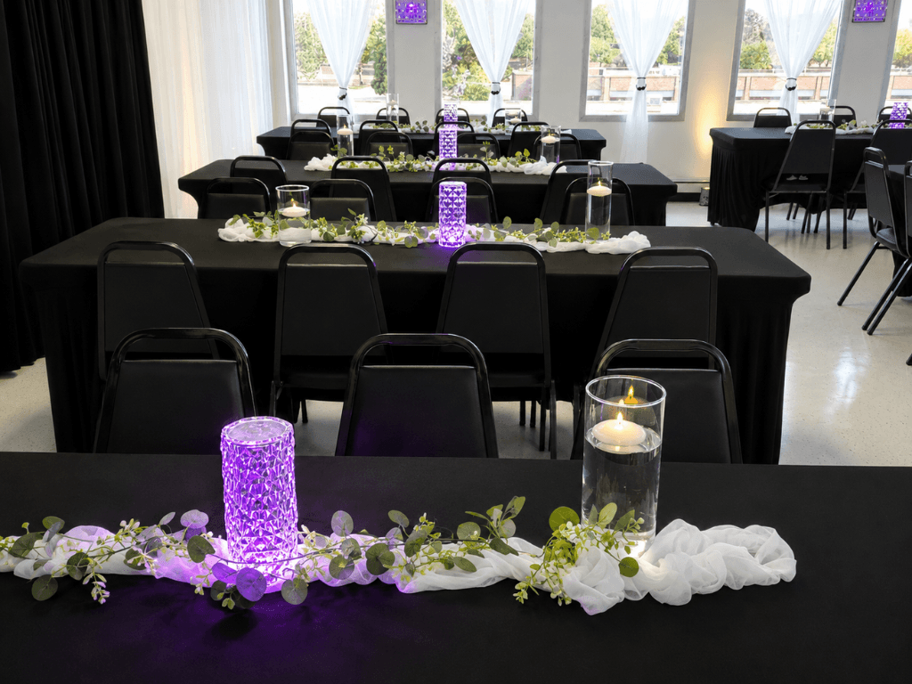 Black banquet tables with purple light and candle centerpieces