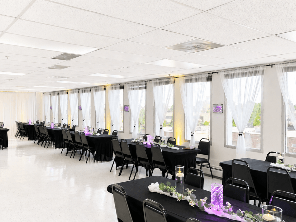 Long banquet setup with black tables and uplights