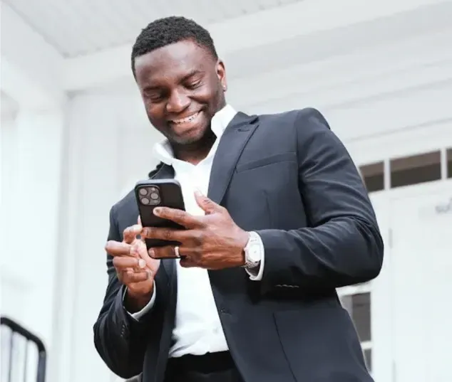 Manny Oloyede smiling and operating his phone. 