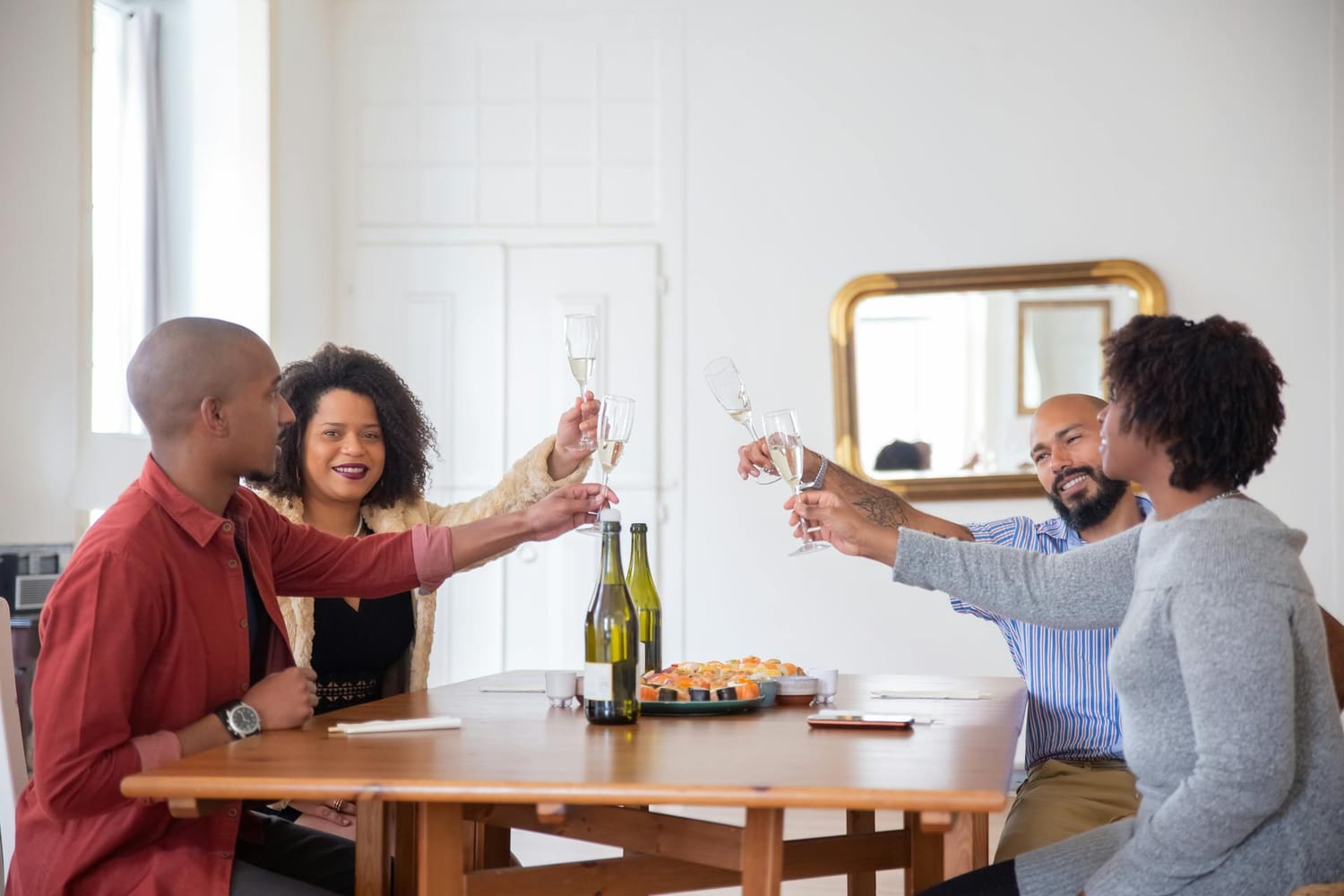 Group of friends raising glasses together during a toast at home.