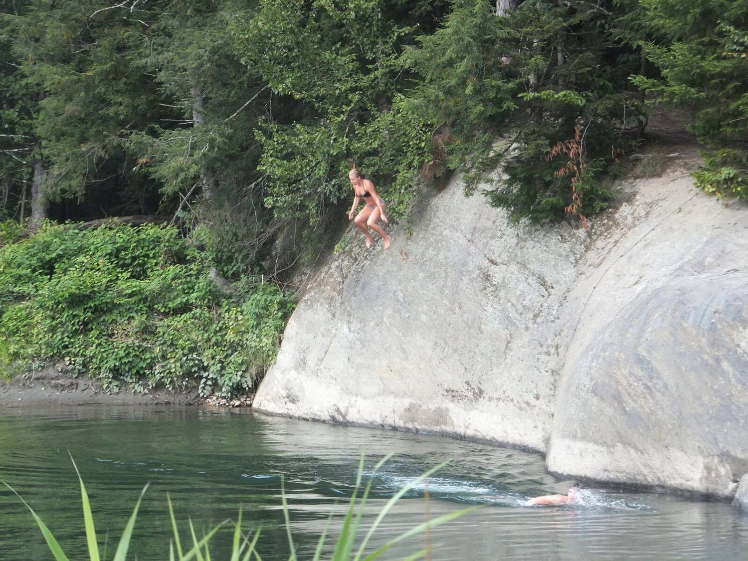 Woman jumping from a rock into the Mad River in Waitsfield, Vermont