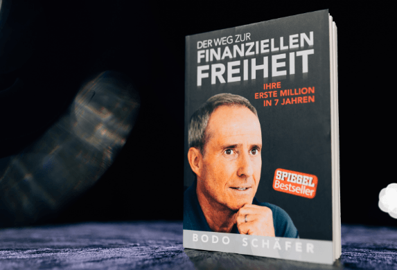 Buch Der Weg zur finanziellen Freiheit von Bodo Schäfer steht auf einem Tisch, Cover mit Porträt des Autors und Hinweis auf Spiegel Bestseller sowie Ziel erste Million in sieben Jahren.