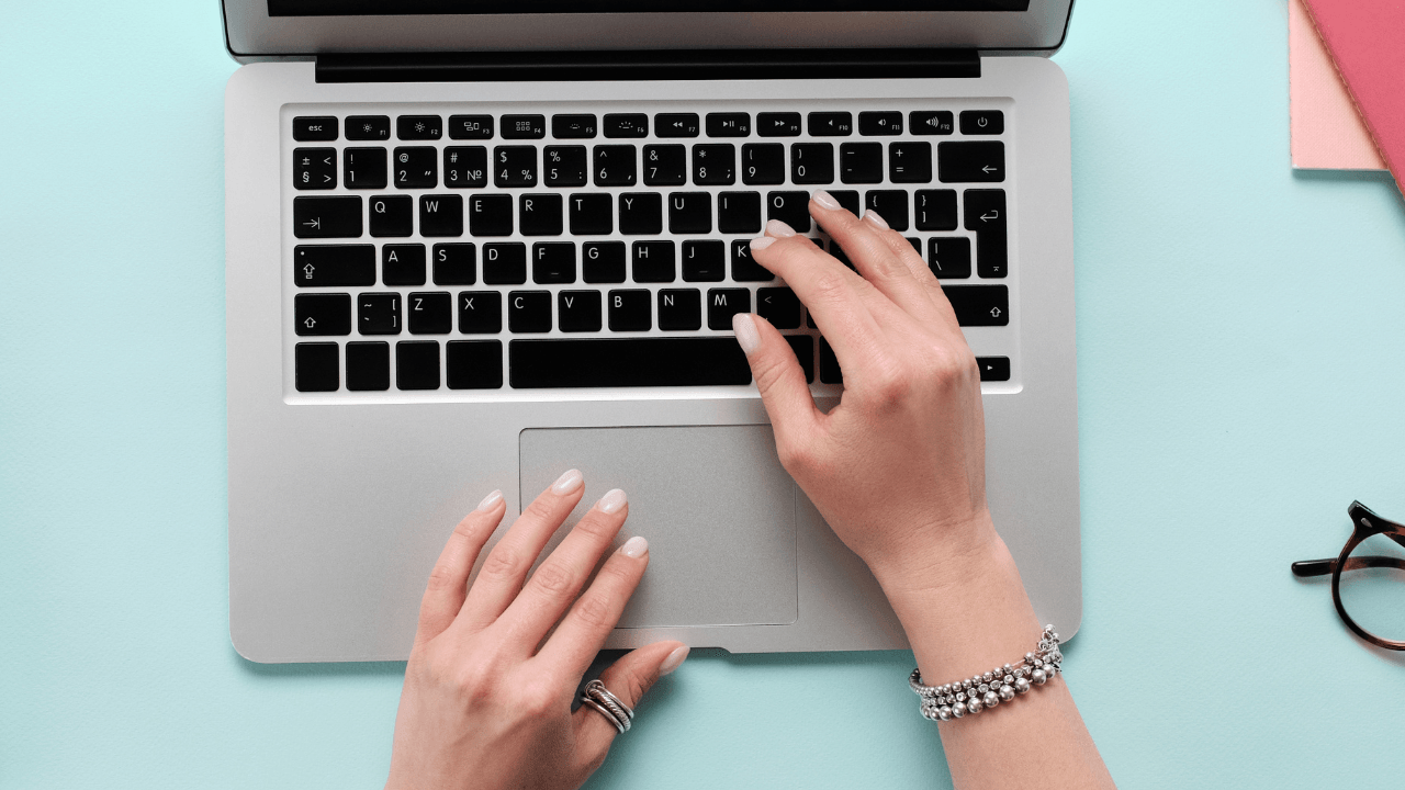 Kobiece dłonie piszą na klawiaturze laptopa — ujęcie symbolizujące dołączenie do społeczności.