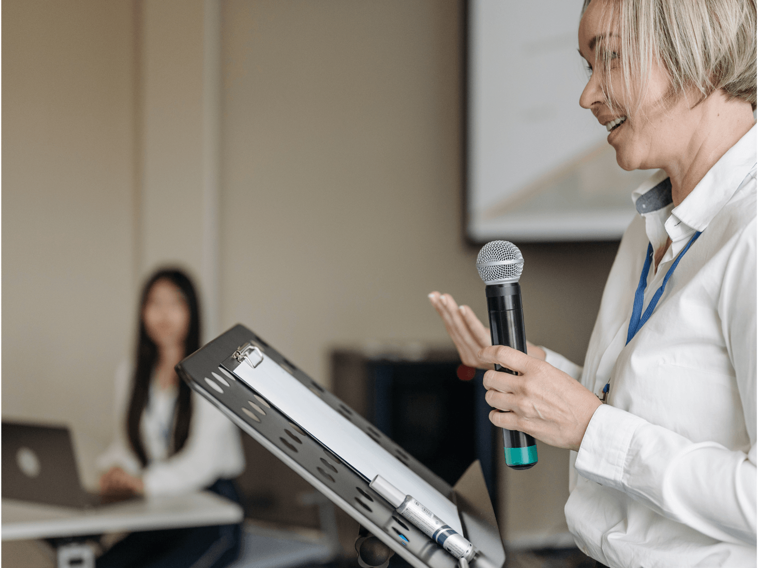 Kobieta prowadząca prelekcję z mikrofonem podczas firmowego warsztatu o finansach i wellbeing